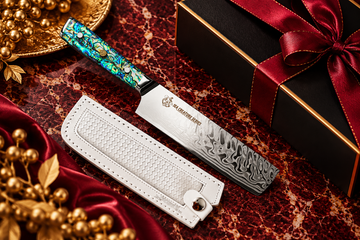 Premium Damascus chef’s knife with iridescent handle and white sheath on burgundy marble with gold accents.