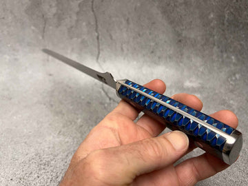 Blue-handled folding knife held in hand